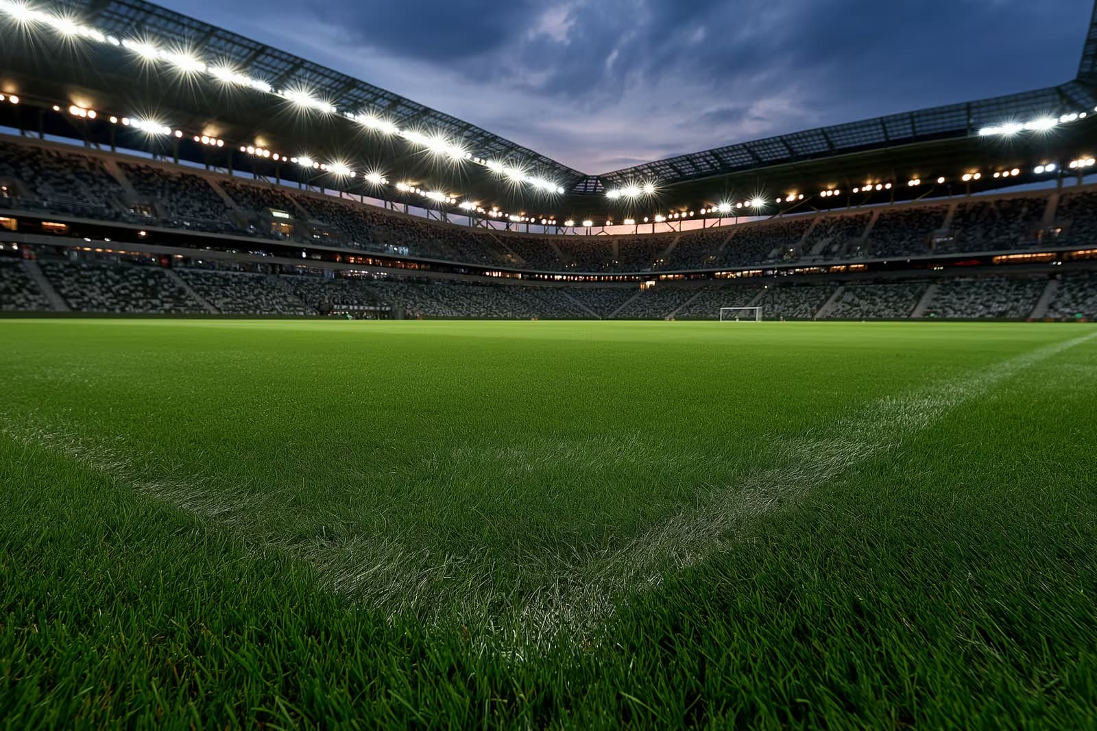 Osvětlený fotbalový stadion za soumraku před večerním zápasem.